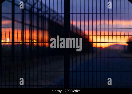 Die Silhouette des eisernen Zauns in der Nähe des Flughafens bei Sonnenuntergang. Selektiver Fokus. Stockfoto