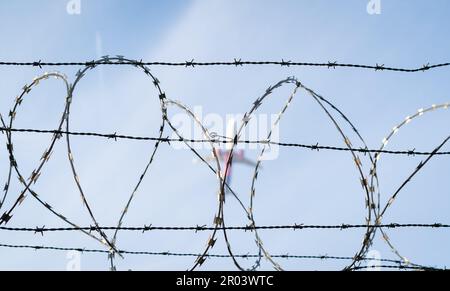 Zaun mit Stacheldraht. Flugzeug im Hintergrund. Stockfoto