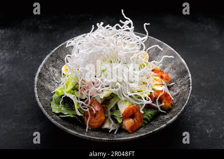 Caesar Salat mit gegrillten Garnelen und knusprigen Reisstäbchen Stockfoto