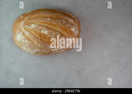 Genießen Sie den Geschmack von frisch gebackenem Brot mit diesem hausgemachten weißen, rustikalen Laib. Das perfekt gebackene, ovale Brot bietet eine knusprige und krustige Extraktion. Stockfoto