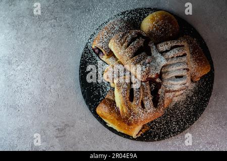 Lassen Sie sich von der Süße dieser köstlichen mit Blaubeeren gefüllten Brötchen verwöhnen, die auf einem rustikalen Teller serviert werden. Diese flauschigen und weichen Brötchen sind gefüllt mit saftigen Blaubeeren Stockfoto