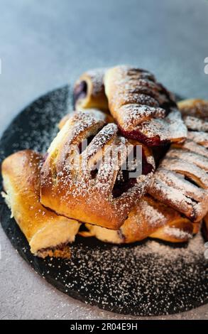 Lassen Sie sich von der Süße dieser köstlichen mit Blaubeeren gefüllten Brötchen verwöhnen, die auf einem rustikalen Teller serviert werden. Diese flauschigen und weichen Brötchen sind gefüllt mit saftigen Blaubeeren Stockfoto