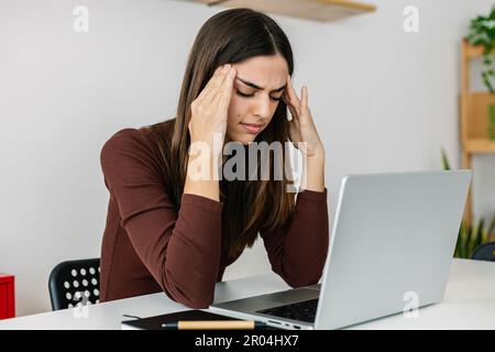 Junge Geschäftsfrau, die im Home Office mit einem Notebook arbeitet Stockfoto
