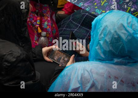 London, Großbritannien. 6. Mai 2023 Die Leute schauen sich den Krönungsdienst auf ihrem Handy an. Zusammen mit Hunderttausenden von Menschen aus der ganzen Welt trotzen sie dem Wetter, um die Prozession zur Krönung von König Karl III. Und Königin Camilla am Samstag, den 6. Mai 2023, zu sehen. Kredit: Kiki Streitberger / Alamy Live News Stockfoto