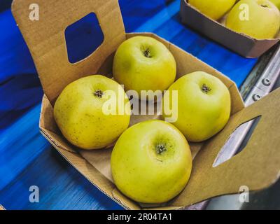 Schachteln mit goldenen, köstlichen Äpfeln auf dem Förderband, bereit für die Verpackung in der Fabrik Stockfoto