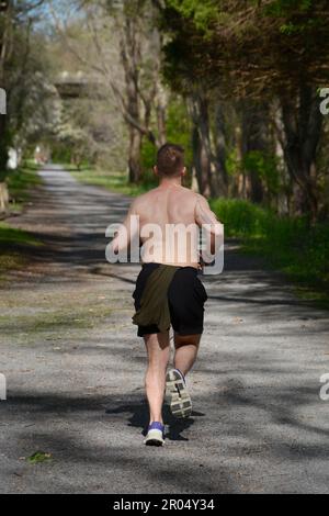 Ein junger Mann joggt auf dem öffentlichen Virginia Creeper Trail in Abingdon, Virginia. Stockfoto