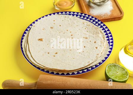 Platte mit dünnem Lavasch und Zutaten auf gelbem Hintergrund Stockfoto