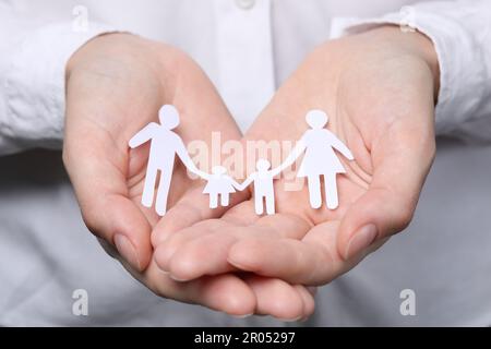 Eine Frau, die Familienfiguren in Papierform hält, Nahaufnahme. Versicherungskonzept Stockfoto