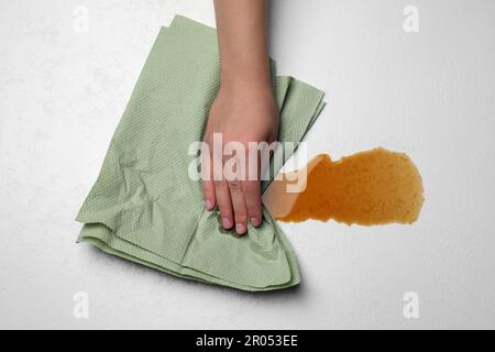 Frau, die verschütteten Kaffee mit einem Papierhandtuch auf einem leichten Tisch abwischte, Draufsicht Stockfoto