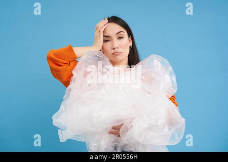 Umweltaktivismus und Recycling. Junge asiatische Frau mit lästigem Gesicht, müde von Unwissenheit für die Umwelt, hält Plastikabfall in der Hand, sieht verärgert aus. Stockfoto