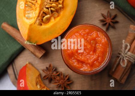 Glas mit köstlicher Kürbismarmelade und Zutaten auf Holzbrett, flach liegend Stockfoto