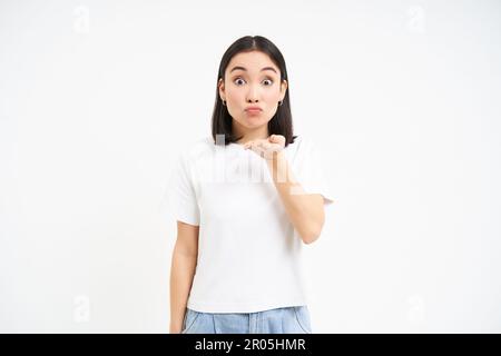 Hübsche koreanische Frau, schickt Luftkuss, bläst mwah vor der Kamera mit niedlichem, albernem Gesicht, steht auf weißem Hintergrund Stockfoto