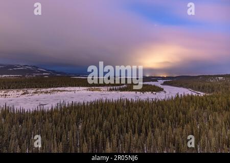 Atemberaubende arktische Sonnenaufgänge im Winter entlang des Yukon River mit pastellfarbenen Rosa, die die Landschaft darunter treffen. Wildnistourismus. Stockfoto