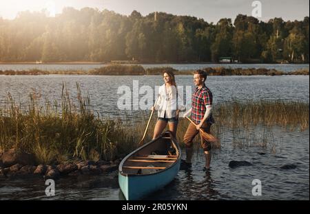 Warum Kanu allein fahren, wenn man es zusammen machen kann. Ein junges Paar, das eine Kanufahrt auf dem See macht. Stockfoto