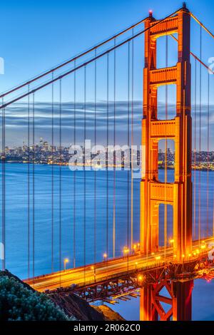 Details der berühmten Golden Gate Bridge bei Sonnenaufgang mit der Skyline von San Francisco im Hintergrund Stockfoto