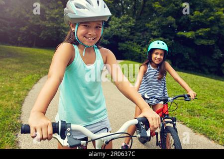 Meine beste Freundin und ich machen eine Fahrradtour. Zwei junge Mädchen machen eine Fahrradtour im Park. Stockfoto