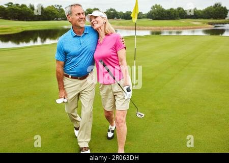 Das Spiel brachte uns näher zusammen. Ein reifes Paar, das zusammen Golf spielt. Stockfoto