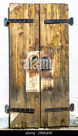 Geschlossenes altes verwittertes Holztor mit geschmiedeten Metallscharnieren der antiken Kirche Stockfoto
