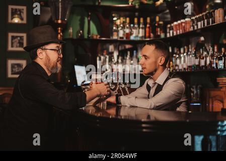 Der Barkeeper an der Bar serviert einem männlichen Gast im Pub Bier im Glas Stockfoto