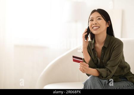 Aisan mit Kreditkarte in der Hand und ruft die Bank an Stockfoto