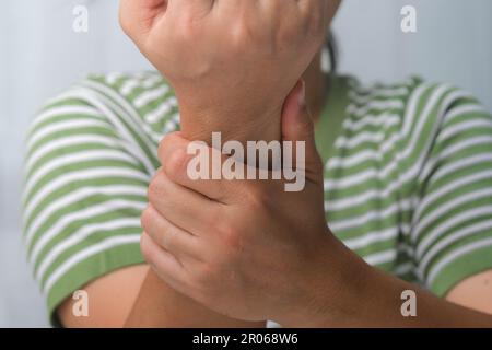 Frau mit Handgelenkschmerzen, Taubheitsgefühl oder Karpaltunnelsyndrom, Arthritis, neurologische Erkrankung. Nahaufnahme der Hand einer Frau, die ein schmerzhaftes Gelenk hält. Stockfoto