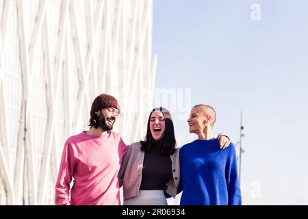 Fröhliches Trio von Freunden, die während eines Spaziergangs lachen Stockfoto
