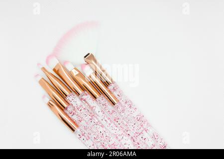 Make-up-Pinsel-Set aus Rosengold mit glitzernden Griffen auf weißem Hintergrund Stockfoto