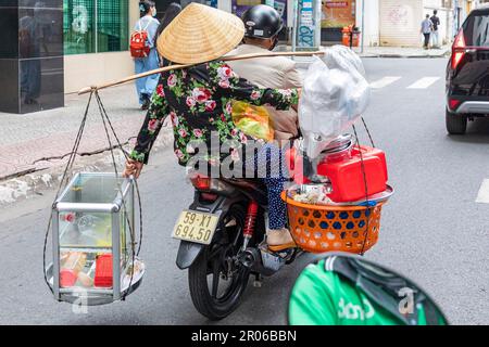 Vietnamesische Dame mit Bambushut, Koffer und Motorradfahrer, Ho-Chi-Minh-Stadt, Vietnam Stockfoto