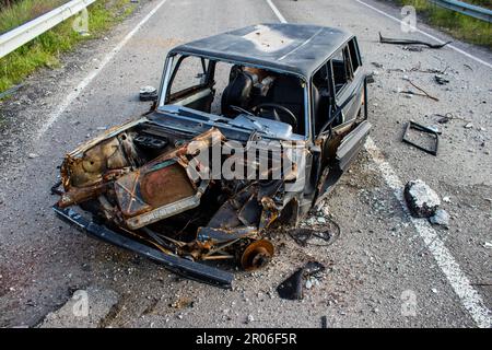 Auf der Lyman-Straße wurde ein ziviles Auto von russischen Soldaten vor der Brücke zerstört, die absichtlich von der ukrainischen Armee in die Luft gesprengt wurde, um sie zu verhindern Stockfoto