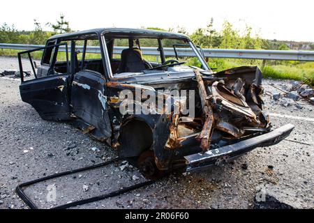 Auf der Lyman-Straße wurde ein ziviles Auto von russischen Soldaten vor der Brücke zerstört, die absichtlich von der ukrainischen Armee in die Luft gesprengt wurde, um sie zu verhindern Stockfoto