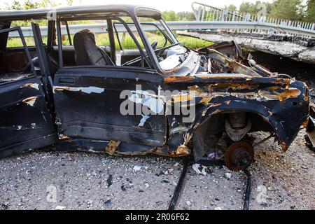 Auf der Lyman-Straße wurde ein ziviles Auto von russischen Soldaten vor der Brücke zerstört, die absichtlich von der ukrainischen Armee in die Luft gesprengt wurde, um sie zu verhindern Stockfoto