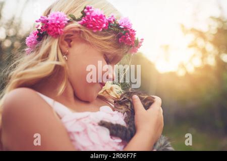 Kitty Delight. Ein kleines Mädchen hält ein Kätzchen und streichelt es, während es draußen in der Natur steht. Stockfoto
