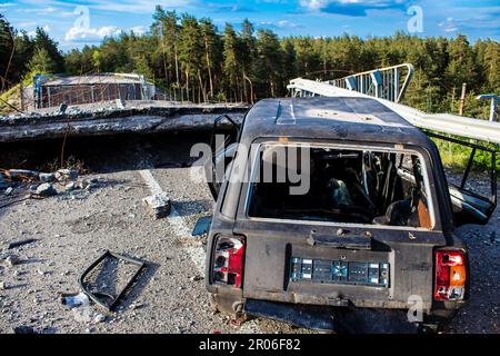 Auf der Lyman-Straße wurde ein ziviles Auto von russischen Soldaten vor der Brücke zerstört, die absichtlich von der ukrainischen Armee in die Luft gesprengt wurde, um sie zu verhindern Stockfoto