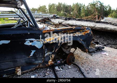 Auf der Lyman-Straße wurde ein ziviles Auto von russischen Soldaten vor der Brücke zerstört, die absichtlich von der ukrainischen Armee in die Luft gesprengt wurde, um sie zu verhindern Stockfoto