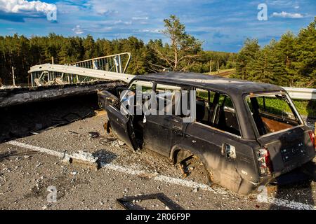 Auf der Lyman-Straße wurde ein ziviles Auto von russischen Soldaten vor der Brücke zerstört, die absichtlich von der ukrainischen Armee in die Luft gesprengt wurde, um sie zu verhindern Stockfoto