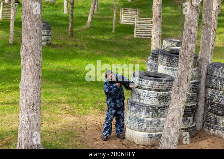 Ein junger Mann, der getarnt Laser-Tag auf einem speziellen Waldspielplatz spielte. Laser Tag ist ein militärisches taktisches Kommandospiel mit sicheren Laserwaffen Stockfoto