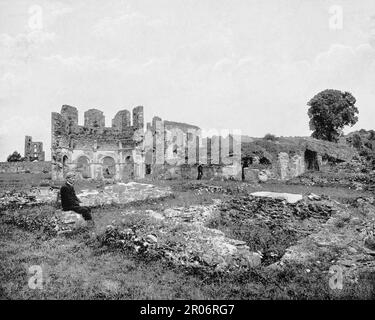 Besucher der Mellifont Abbey, einer Zisterzienserabtei im County Louth, Irland, aus dem späten 19. Jahrhundert. 1142 war es die erste Abtei des Ordens, die in Irland gebaut wurde. Nach ihrer Auflösung im Jahr 1539 wurde die Abtei zu einem privaten Herrenhaus und diente 1690 während der Schlacht um die Boyne als Hauptquartier von William of Orange. Nur ein kleiner Teil der ursprünglichen Abtei ist übrig, außer einem Lavabo aus dem 13. Jahrhundert (wo die Mönche sich vor dem Essen die Hände gewaschen haben), einigen romanischen Bögen und einem Kapitelhaus aus dem 14. Jahrhundert. Stockfoto