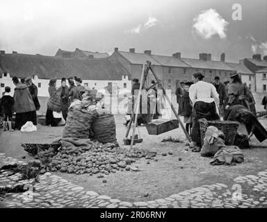 Ein Blick aus dem späten 19. Jahrhundert auf den Kartoffelmarkt am Bolton Square in Drogheda, County Louth an der Ostküste Irlands. Die Einheimischen können dabei gesehen werden, wie sie sich unterhalten und das allgegenwärtige Wasser kaufen. Es war auch der Ort für andere Märkte, die Butter, Fleisch, Fisch und Pferde verkaufen. Stockfoto