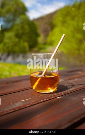 Die sommerliche Atmosphäre entsteht aus diesem Glas Fruchtsaft, die Sonne fällt auf die Flüssigkeit und auf den verschwommenen Hintergrund. Stockfoto