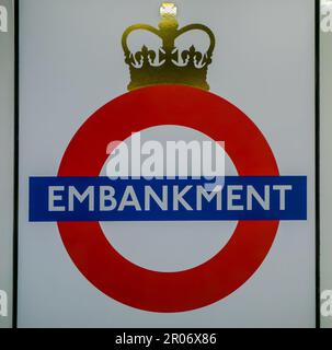 Das berühmte U-Bahnhofsschild mit einem roten Kreis mit blauem Streifen, das Millionen von Pendlern bekannt ist, ist auf einem Bahnhofsschild am Embankment in London zu sehen Stockfoto