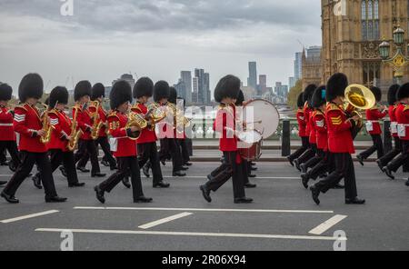 Während sie in vollen Zeremonialkostümen über die Westminster Bridge marschieren, spielt eine Band der Grenadiergarde der Bristischen Armee Musik, während sie marschieren Stockfoto