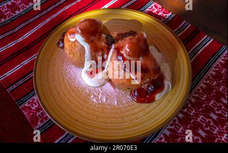 Papanasi - eine traditionelle rumänische Dessert. Der Kuchen wird von drei Donuts in der sauren Sahne und Früchten Marmelade gemacht Stockfoto