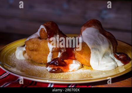 Papanasi - eine traditionelle rumänische Dessert. Der Kuchen wird von drei Donuts in der sauren Sahne und Früchten Marmelade gemacht Stockfoto