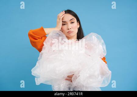 Umweltaktivismus und Recycling. Junge asiatische Frau mit lästigem Gesicht, müde von Unwissenheit für die Umwelt, hält Plastikabfall in der Hand, sieht verärgert aus Stockfoto