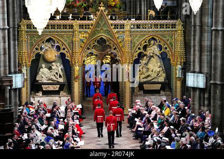 Soldaten gehen an den Gästen vorbei, während sie sich auf den Beginn der Krönungszeremonie von König Charles III. In Westminster Abbey in London vorbereiten. Foto: Samstag, 6. Mai 2023. Stockfoto