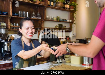 Vietnamesische Kellnerin, die einem Kunden in einem Café Eiscreme serviert Stockfoto