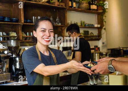 Vietnamesische Kellnerin, die einem Kunden in einem Café Eiscreme serviert Stockfoto