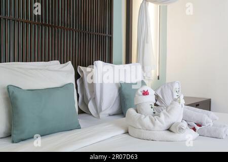 Begrüßungsgetränke mit Blumen und Handtüchern auf dem Bett im Luxushotel bei der Ankunft. Stockfoto