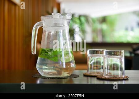 Entgiftungswasser aus Gurken, Limette und Minzblättern in der Kanne im Lounge-Bereich Stockfoto