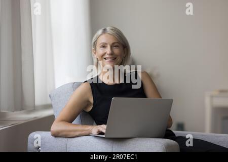 Glückliche, erfolgreiche, freiberufliche Geschäftsfrau, die von zu Hause aus arbeitet Stockfoto